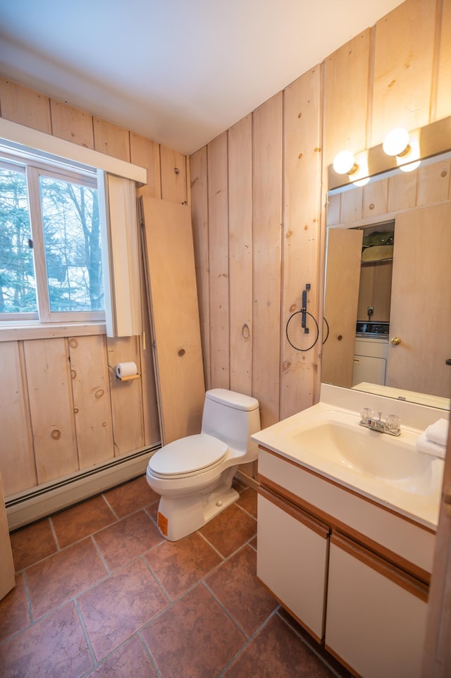 bathroom featuring wooden walls, vanity, a baseboard radiator, and toilet