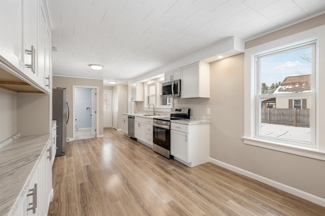 kitchen featuring white cabinets, sink, light stone countertops, light hardwood / wood-style floors, and stainless steel appliances