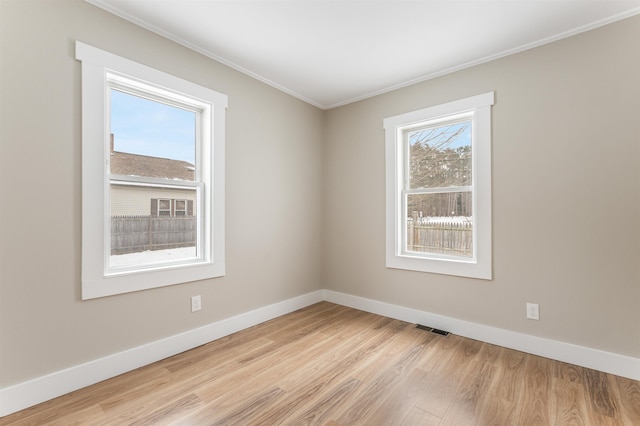 spare room with ornamental molding and light hardwood / wood-style flooring