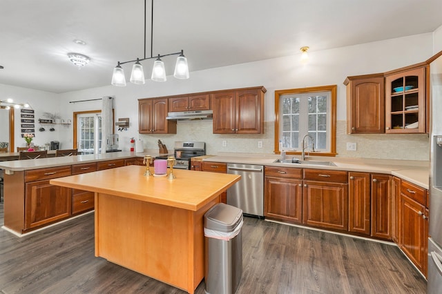 kitchen featuring sink, a kitchen island, dark hardwood / wood-style flooring, kitchen peninsula, and stainless steel appliances