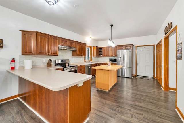 kitchen with kitchen peninsula, appliances with stainless steel finishes, pendant lighting, dark hardwood / wood-style floors, and a kitchen island