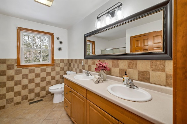 bathroom with tile patterned flooring, vanity, toilet, and tile walls