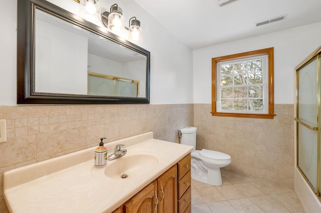 full bathroom featuring tile patterned floors, vanity, toilet, and tile walls