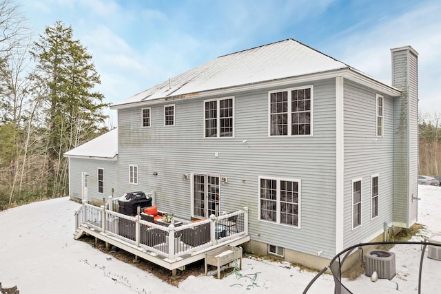 snow covered house featuring central AC unit and a deck