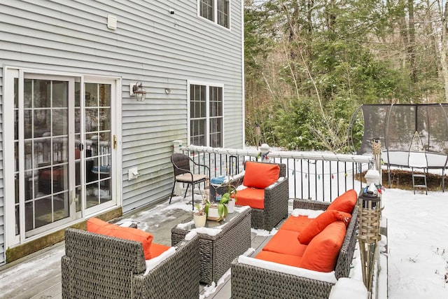 snow covered deck featuring outdoor lounge area and a trampoline