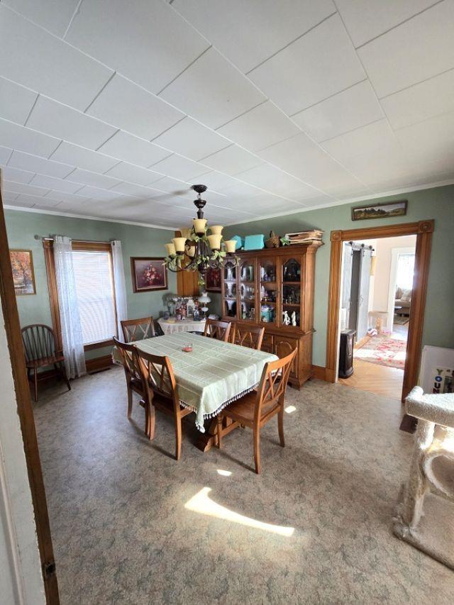 carpeted dining room with a chandelier