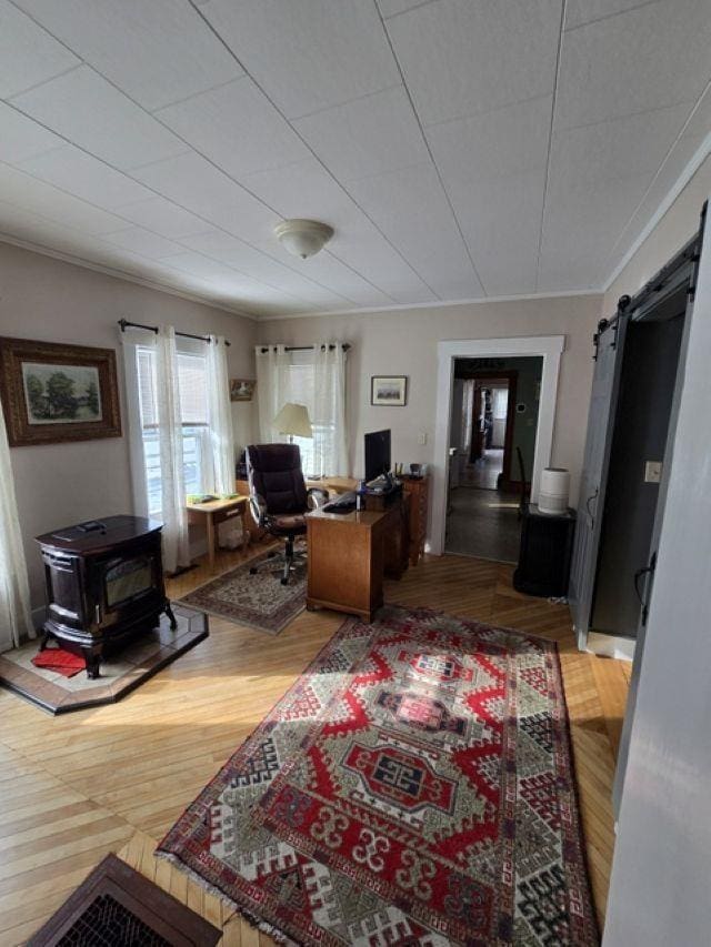 home office with ornamental molding, a barn door, and wood-type flooring