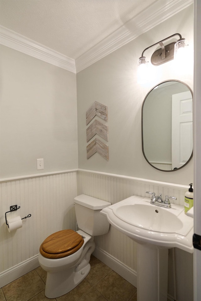 bathroom featuring toilet, tile patterned flooring, a textured ceiling, and ornamental molding