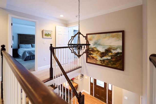 corridor featuring wood-type flooring, ornamental molding, and an inviting chandelier