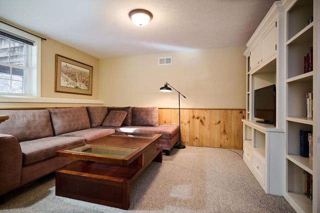 living room featuring wood walls, carpet, and a textured ceiling