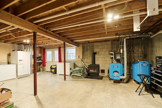 basement with a wood stove, fridge, and white refrigerator with ice dispenser