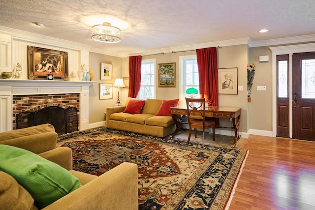 living room with ornamental molding, a chandelier, a textured ceiling, a fireplace, and light wood-type flooring