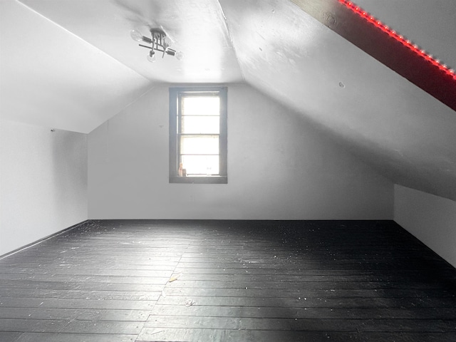 additional living space with hardwood / wood-style flooring and vaulted ceiling