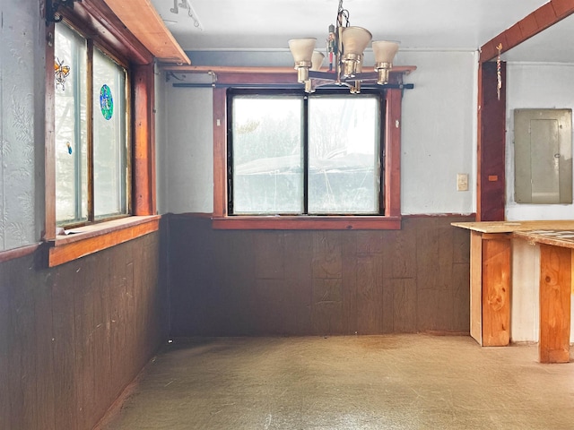 interior space with electric panel, wooden walls, and a chandelier