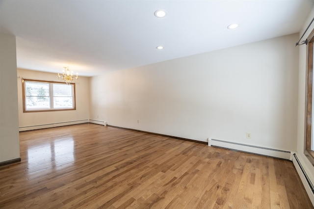 unfurnished room featuring a baseboard radiator, light wood-type flooring, and an inviting chandelier