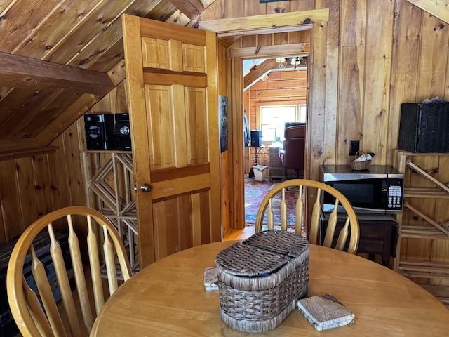 dining area with lofted ceiling and wooden walls