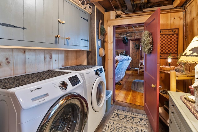 washroom featuring separate washer and dryer, wood walls, and cabinets