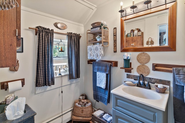 bathroom with vanity, a baseboard heating unit, ornamental molding, and vaulted ceiling