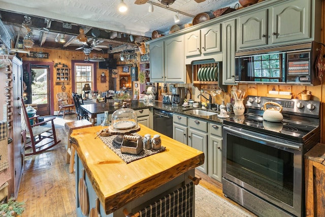 kitchen featuring sink, kitchen peninsula, light hardwood / wood-style floors, wooden walls, and black appliances