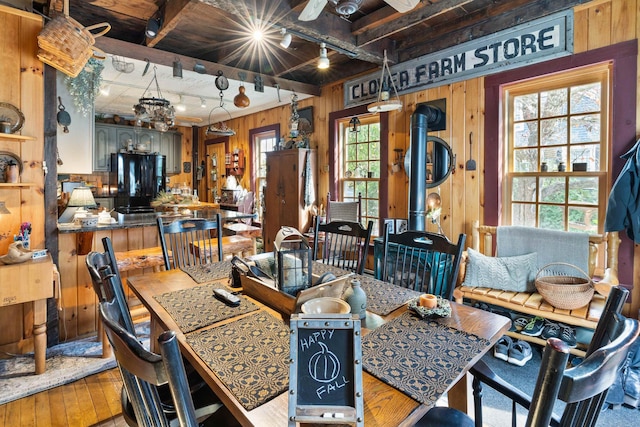 dining area with beam ceiling, wood walls, and wood-type flooring