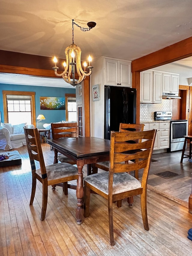 dining area with light hardwood / wood-style floors and a chandelier