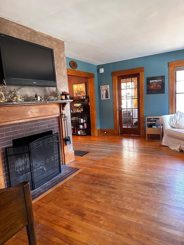 living room featuring a brick fireplace, a wealth of natural light, and hardwood / wood-style flooring