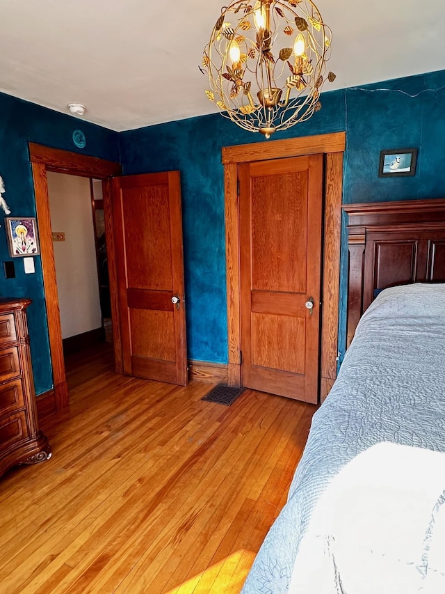 bedroom featuring a closet, light hardwood / wood-style floors, and a notable chandelier