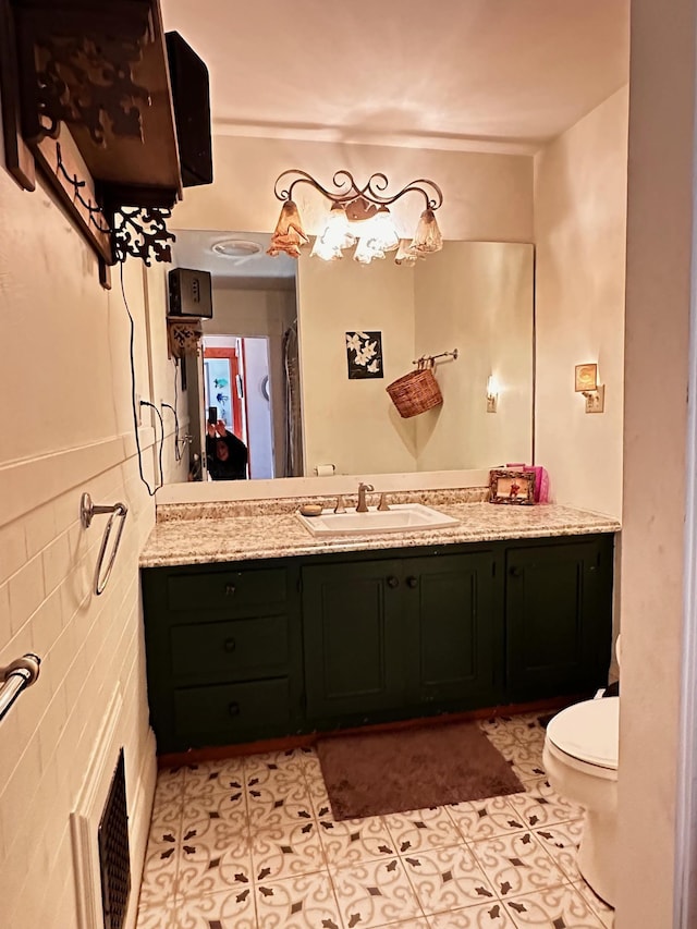 bathroom featuring tile walls, vanity, tile patterned floors, and toilet