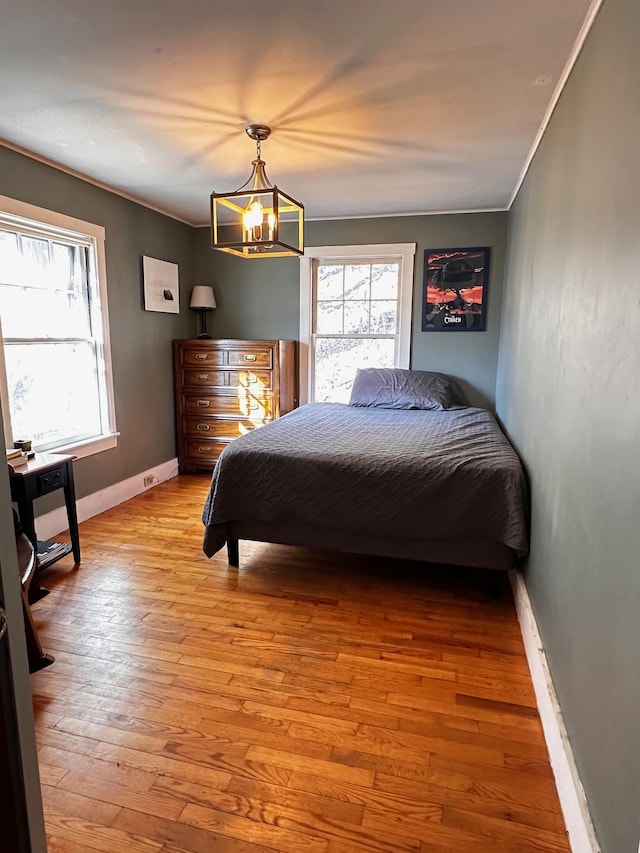 bedroom with light wood-type flooring, crown molding, and a chandelier