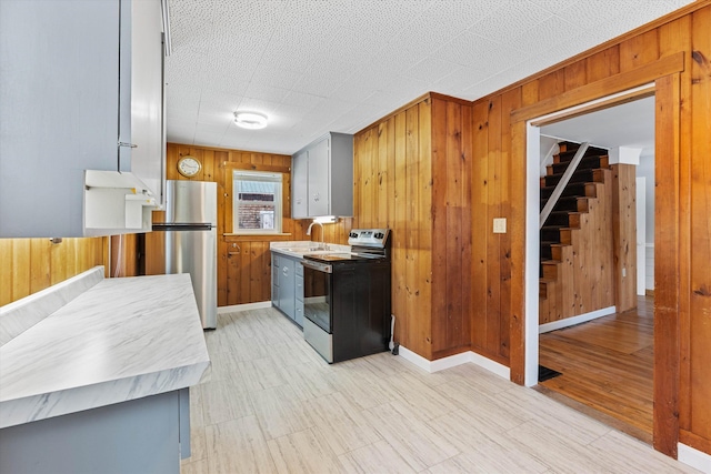 kitchen featuring stainless steel appliances, wood walls, and sink