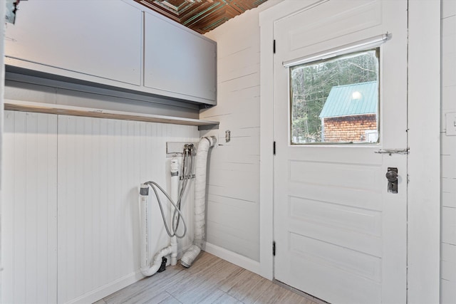 laundry area featuring wood walls and cabinets