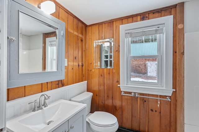 bathroom featuring vanity, toilet, and wood walls