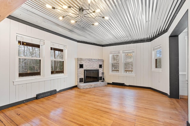 unfurnished living room featuring light hardwood / wood-style floors, a fireplace, and an inviting chandelier