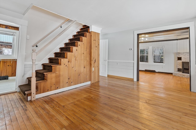 unfurnished living room featuring a fireplace, wooden walls, and light hardwood / wood-style flooring