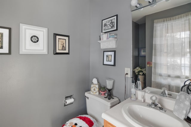 bathroom with toilet, vanity, and a healthy amount of sunlight