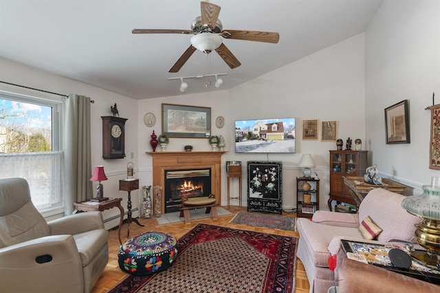 tiled living room with ceiling fan, track lighting, vaulted ceiling, and a baseboard heating unit