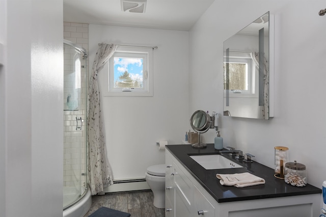 bathroom featuring baseboard heating, toilet, walk in shower, vanity, and hardwood / wood-style flooring