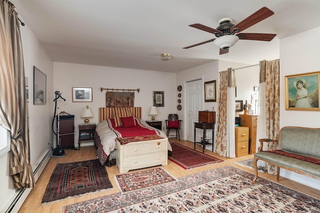 bedroom featuring a baseboard heating unit, ceiling fan, and light hardwood / wood-style floors