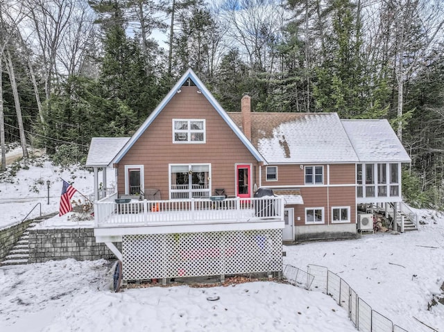 snow covered rear of property featuring ac unit and a wooden deck