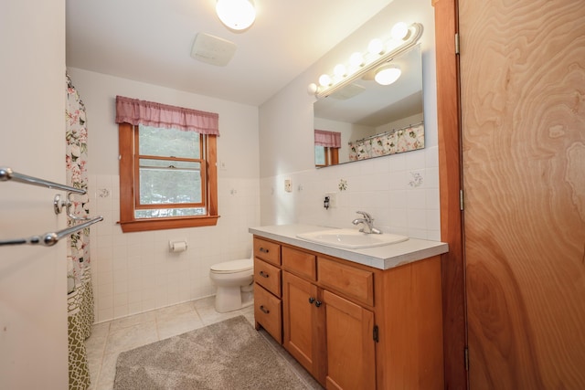 bathroom with vanity, toilet, tile patterned flooring, and tile walls