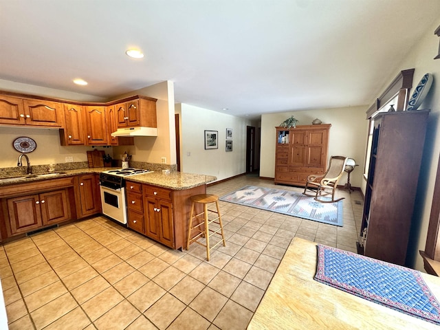 kitchen featuring white range with electric cooktop, a kitchen breakfast bar, kitchen peninsula, light tile patterned floors, and sink