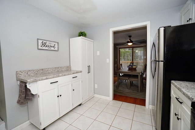 kitchen with ceiling fan, stainless steel fridge, white cabinetry, and light tile patterned flooring