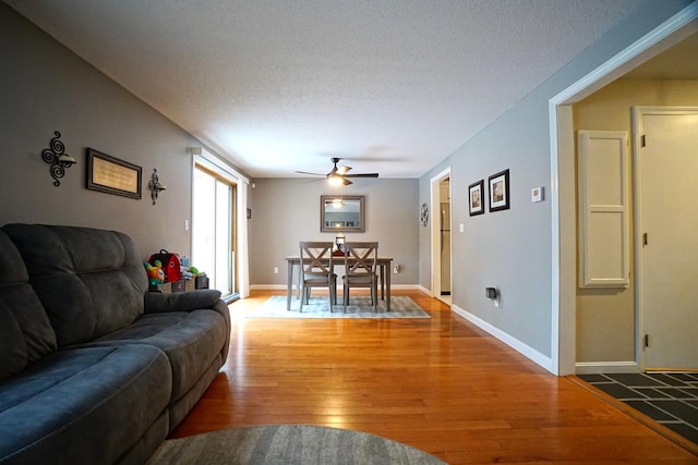 living room featuring a textured ceiling, hardwood / wood-style floors, and ceiling fan