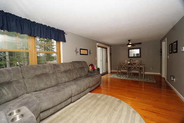 living room with a textured ceiling, ceiling fan, and hardwood / wood-style floors