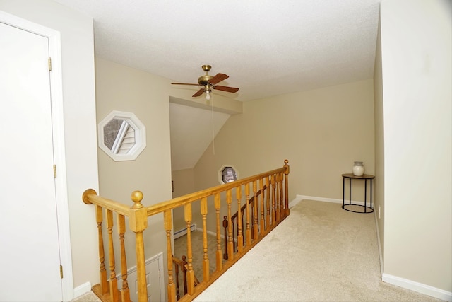 corridor with lofted ceiling, a baseboard heating unit, light carpet, and a textured ceiling