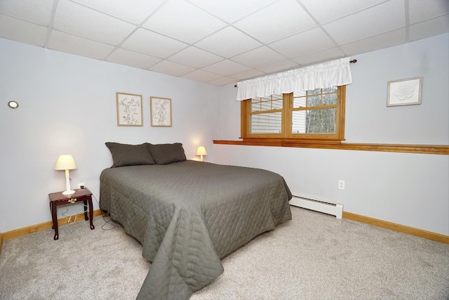 carpeted bedroom with a baseboard heating unit and a drop ceiling