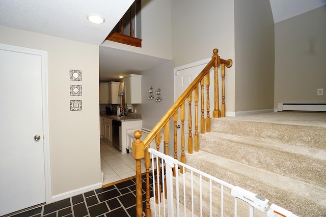 stairway with sink, tile patterned flooring, and a baseboard heating unit