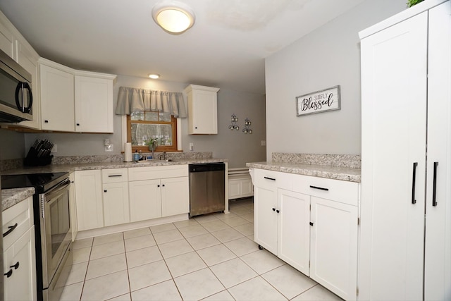 kitchen with sink, stainless steel appliances, white cabinets, and light tile patterned flooring