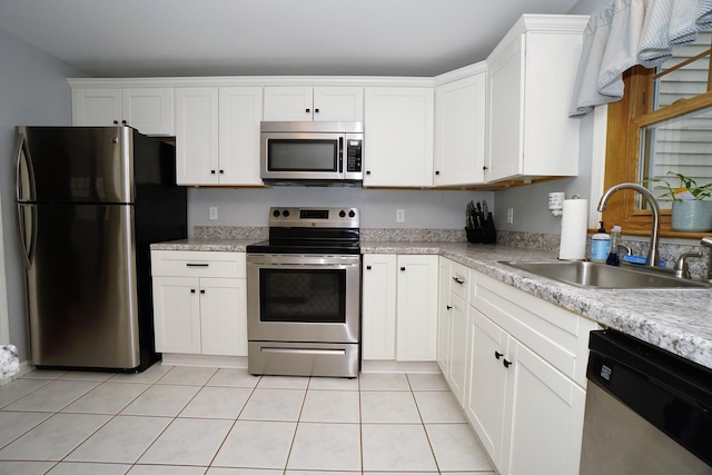 kitchen with appliances with stainless steel finishes, white cabinetry, sink, and light tile patterned floors