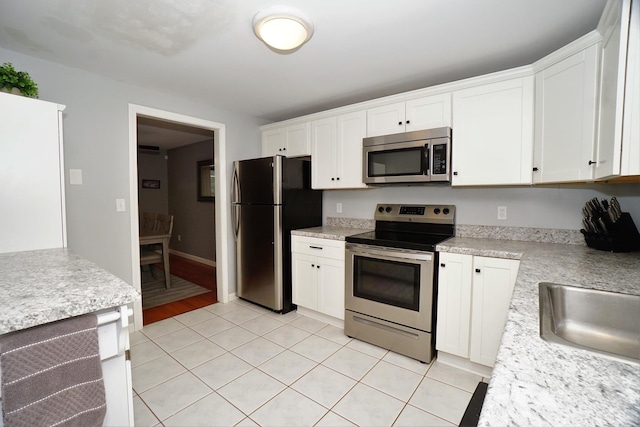 kitchen featuring stainless steel appliances, white cabinets, light tile patterned flooring, and sink